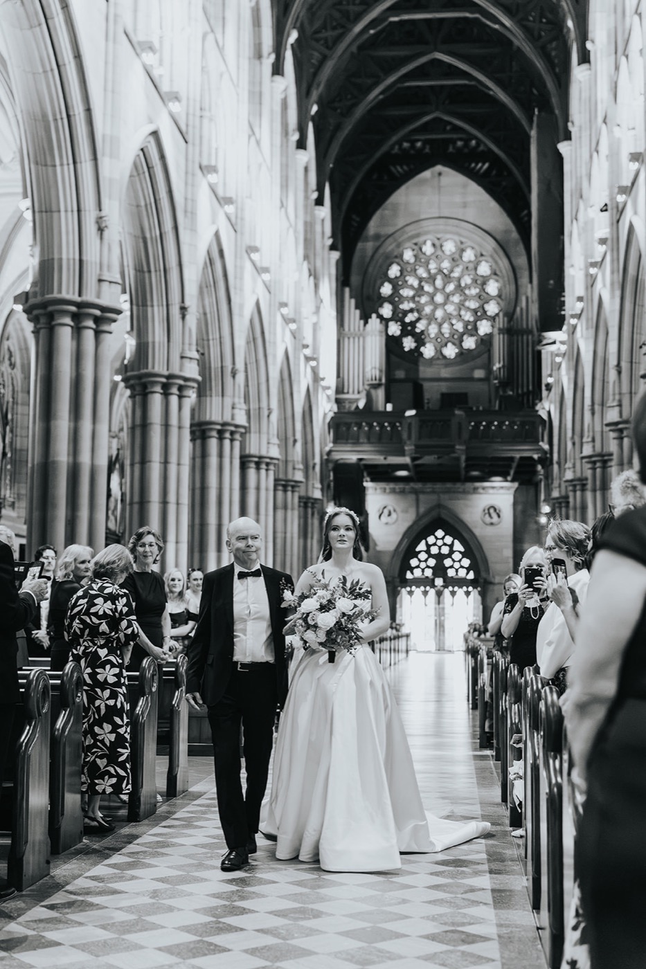 Black and white of the bride walking down the cathedral aisle