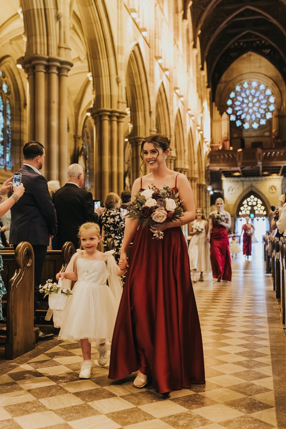 Bridesmaid and flower girl processing down the cathedral aisle