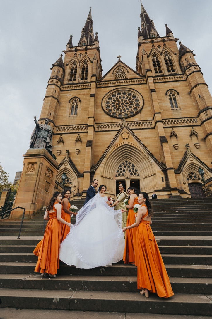 Bridesmaids lifting the bride's veil on the cathedral steps