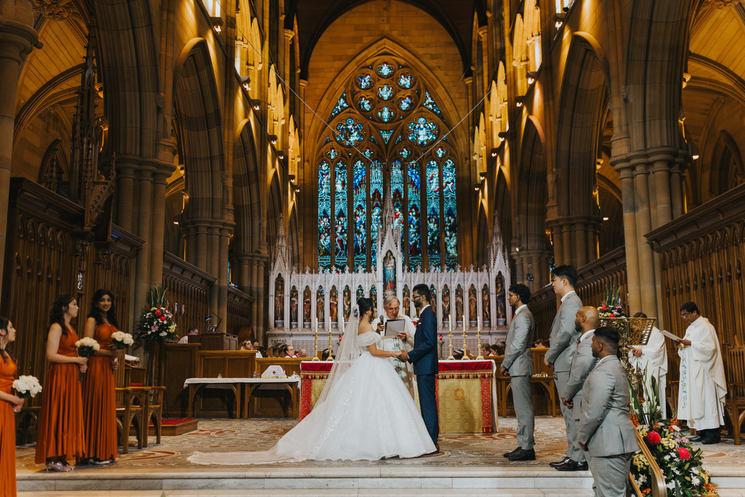 Couple exchanging vows at the cathedral altar beneath the stained glass