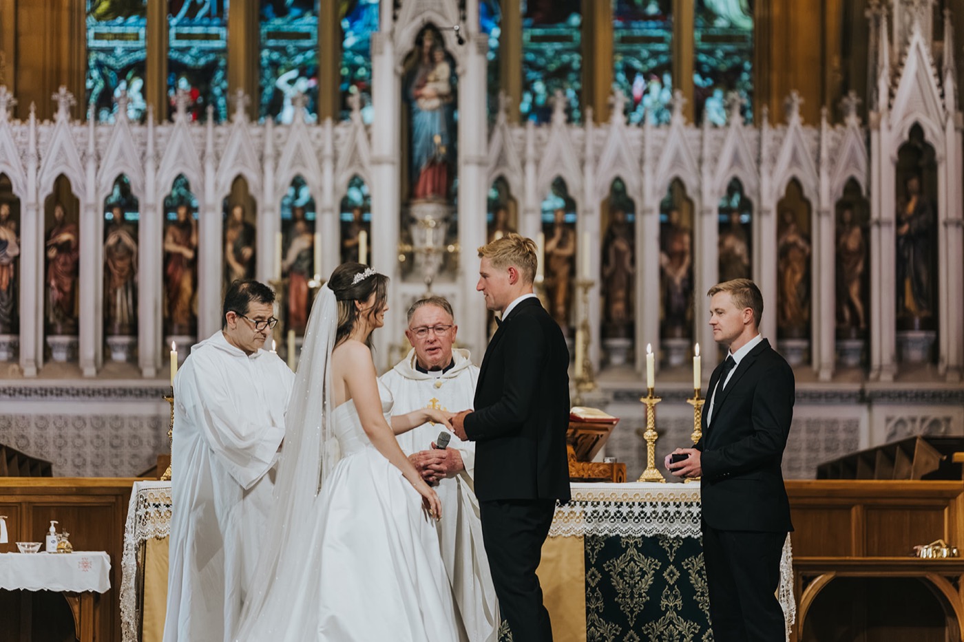 Couple exchanging vows before the priest at the cathedral altar