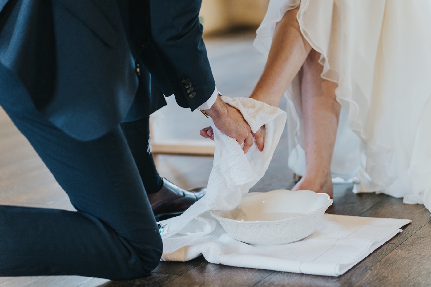 Groom kneeling to wash his bride's feet during the ceremony