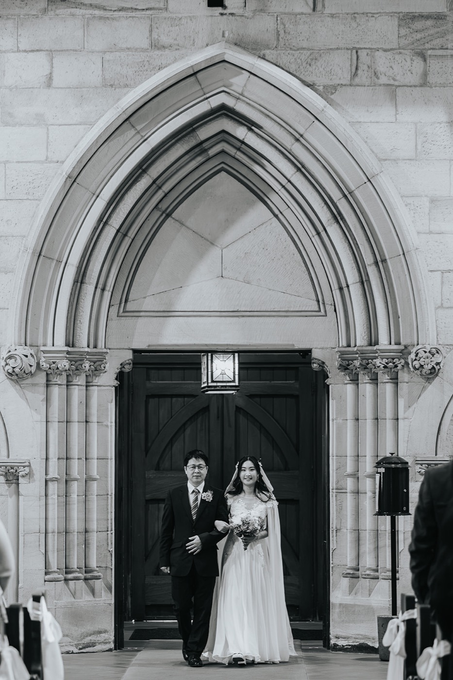 Black and white of the couple at the church's gothic door