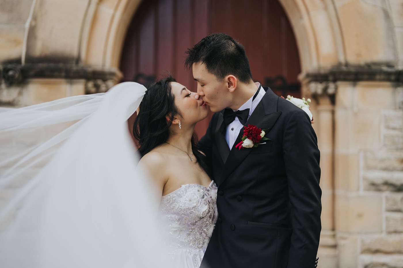 Couple kissing at the arched door of a sandstone church