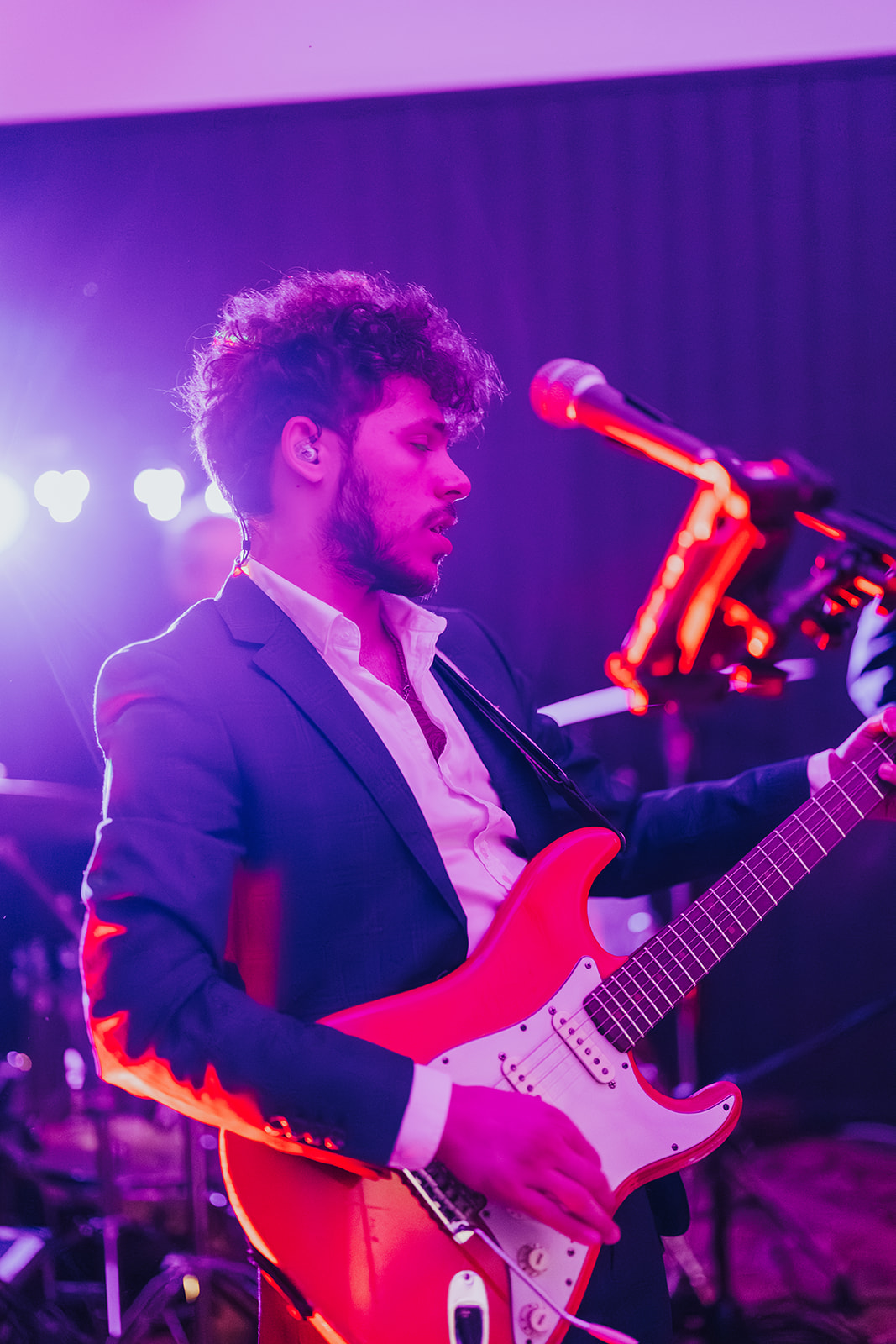 The band's guitarist under purple stage lights