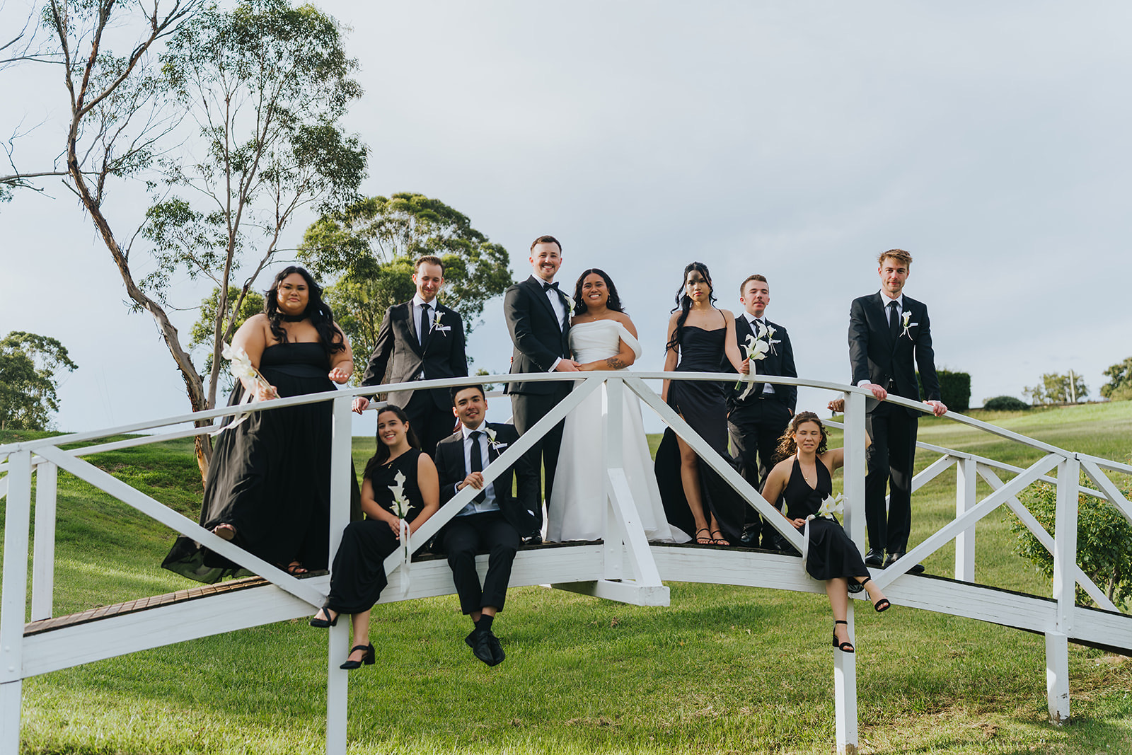 The bridal party celebrating on the white footbridge at La Pera Estate