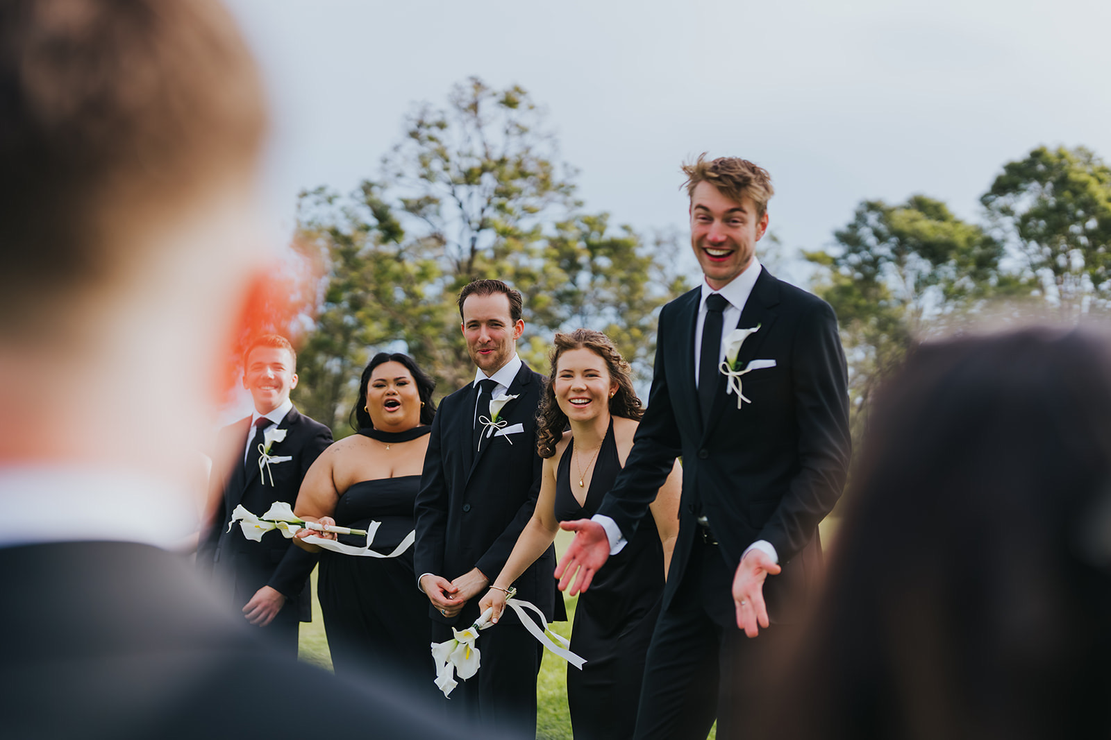 The full bridal party laughing together on the estate lawn
