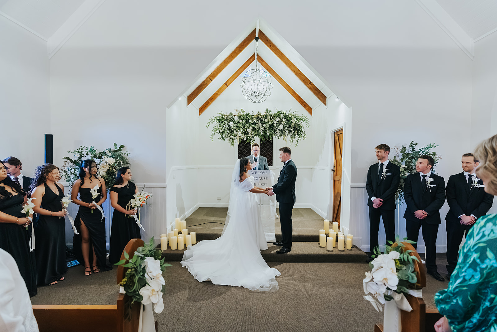 Wide view down the aisle of the chapel as Sophia reaches Lachlan