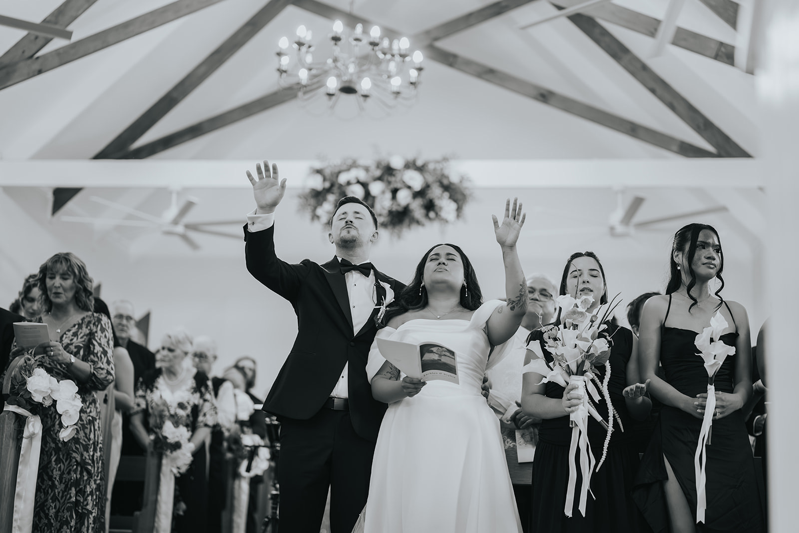 Black and white of the newlyweds celebrating with guests in the chapel