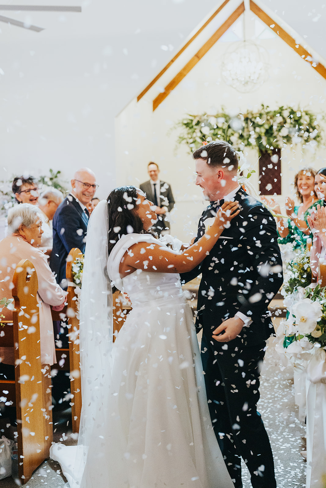 Guests throwing confetti over the couple outside the chapel