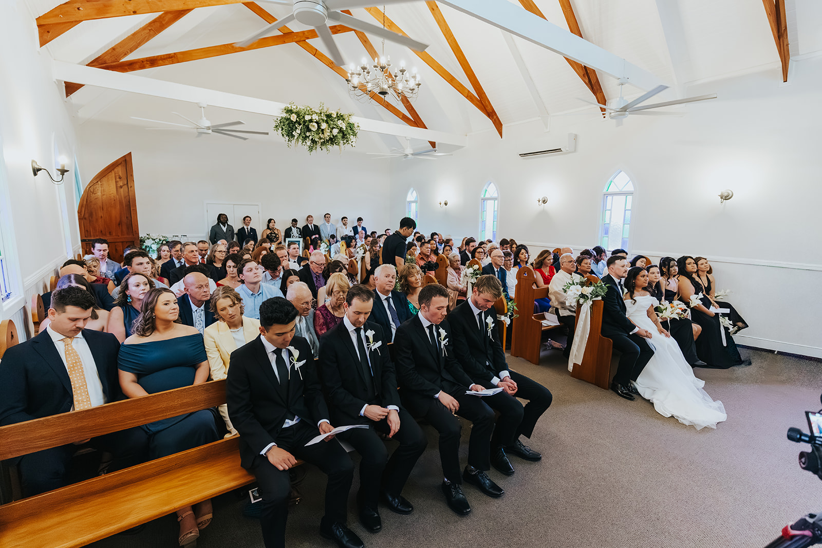 Inside the chapel at La Pera Estate, guests filling the handcrafted pews beneath timber trusses