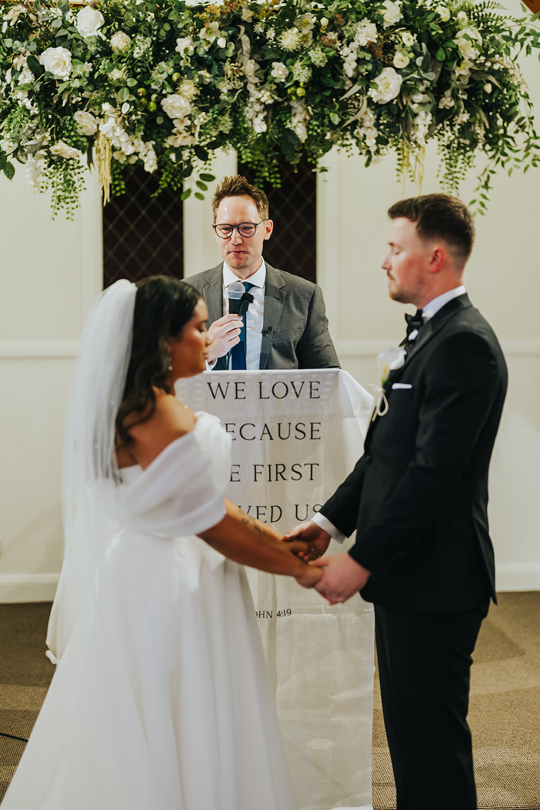 Sophia and Lachlan exchanging vows beneath the greenery at the altar