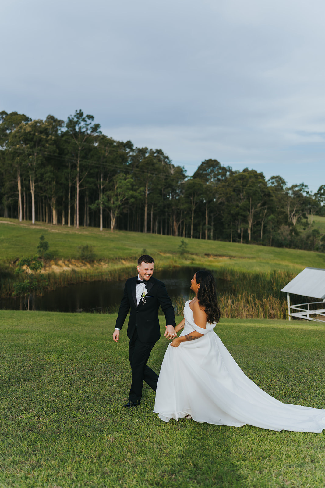 The couple walking through the open paddock with her train behind