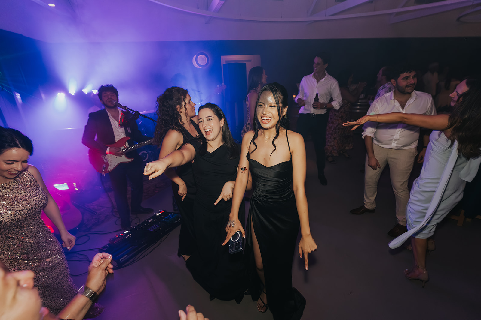 Bridesmaids dancing under coloured party lights