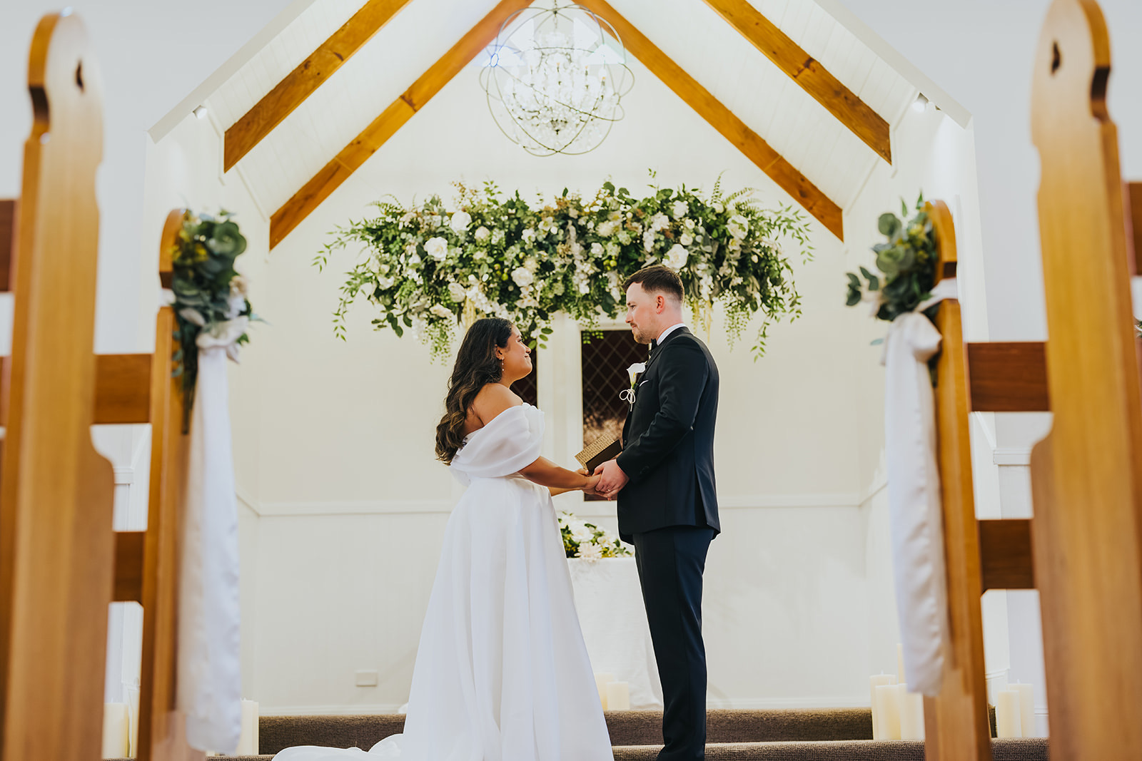 Sophia and Lachlan alone at the front of the white chapel at La Pera Estate for their private vows