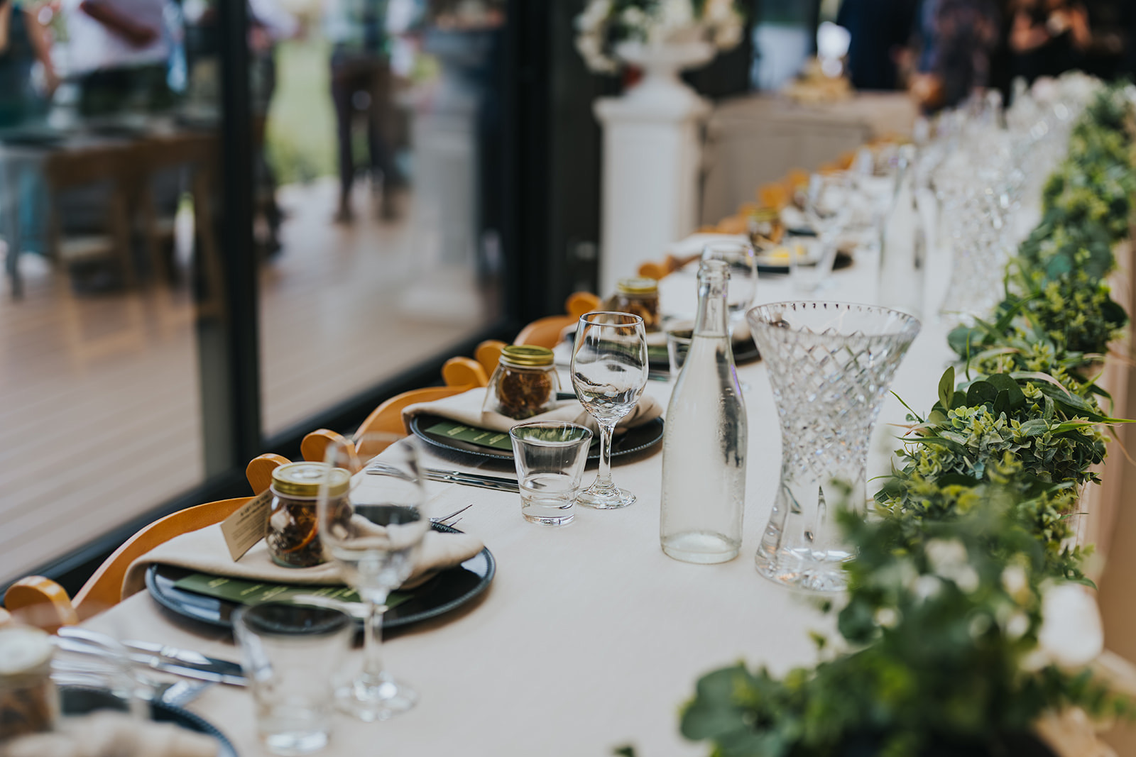 Long reception tables dressed with greenery and candles