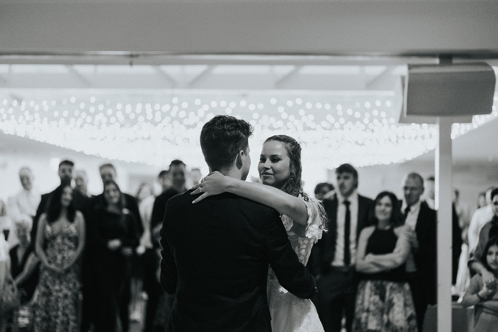 Black and white of the first dance with guests watching