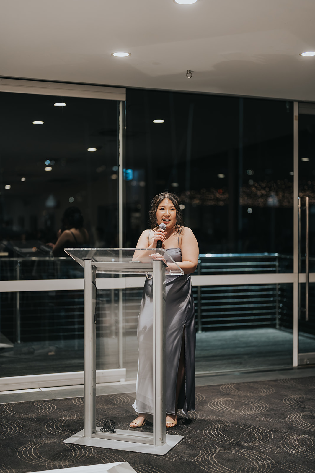 A speech at the lectern in front of the night-time windows