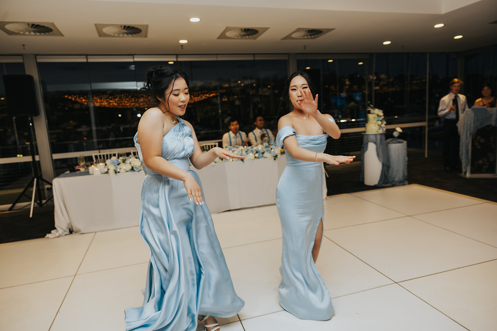 Bridesmaids in powder blue dancing onto the white dance floor