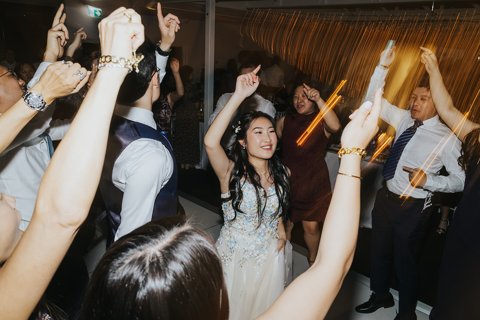 Shaphir surrounded by friends with hands in the air on the dance floor
