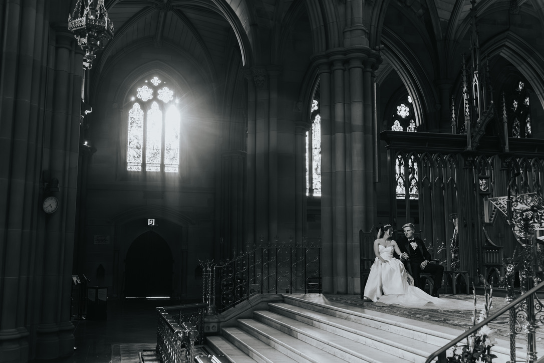 Couple seated in a cathedral as light streams through the windows