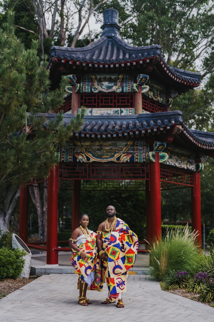 Couple in traditional kente cloth in front of a pagoda