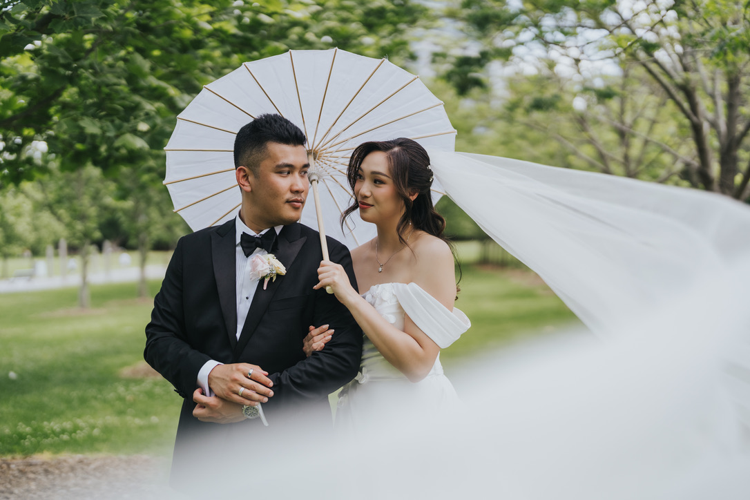 Couple under a paper parasol as the veil sweeps past